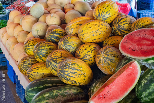 A vibrant display of various melons, watermelon  at a local market stall. Their bright colors and unique patterns emphasize the freshness and seasonal appeal of summer fruits. 