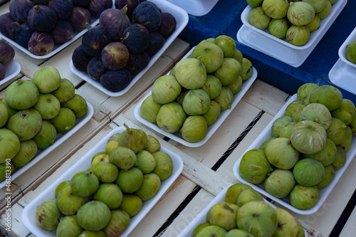 Fresh figs packaged on plastic substrates on the counter on farmer's market. Green and purple figs. Healthy eating