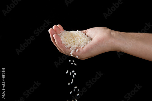 Hands dropping rice grain isolated on black background.