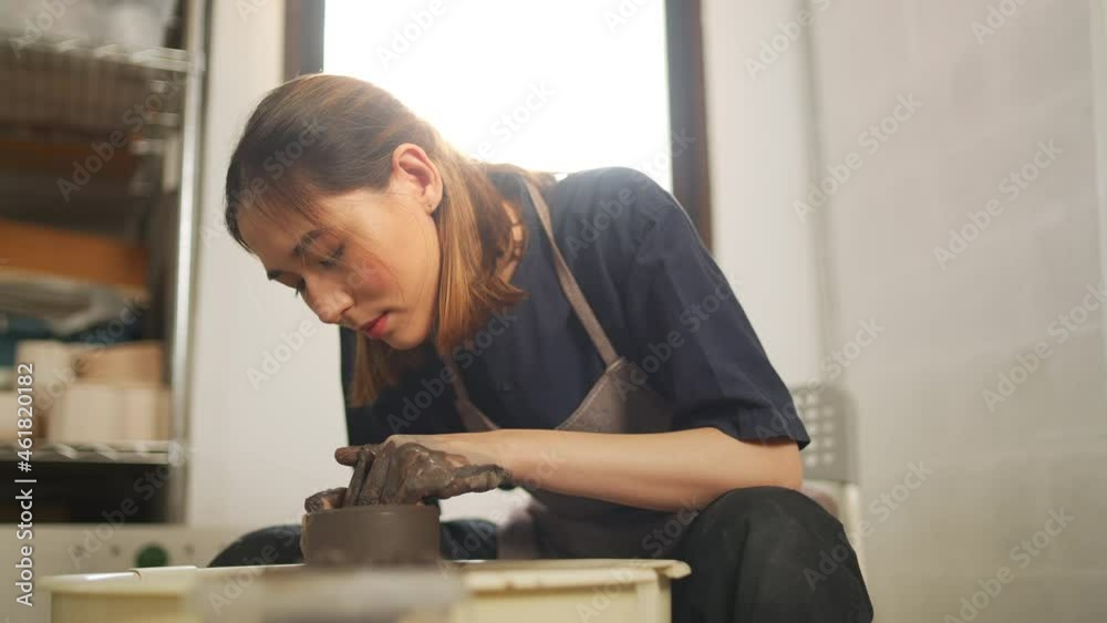 4K Asian woman sculptor artist hands sculpture clay on pottery wheel at ceramic studio. Female craftsman molding raw clay create pottery shapes at workshop. Small business handicraft product concept. 4K Asian woman sculptor artist hands sculpture clay on pottery wheel at ceramic studio. Female craftsman molding raw clay create pottery shapes at workshop. Small business handicraft product concept.
