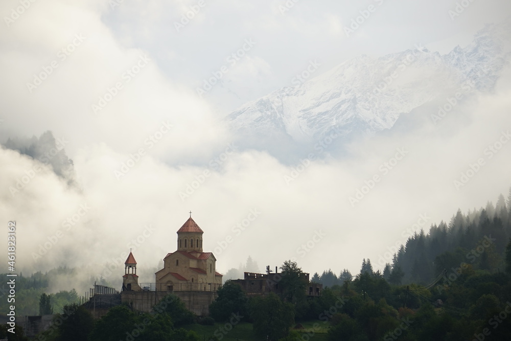 Defensive walls and towers of the castle against the cloudy sky. High quality photo. Beautiful landscape, with hilltop ancient defense tower or tower of souls, with old stone stairs. Georgia.