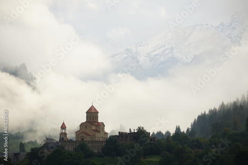 Defensive walls and towers of the castle against the cloudy sky. High quality photo. Beautiful landscape, with hilltop ancient defense tower or tower of souls, with old stone stairs. Georgia.