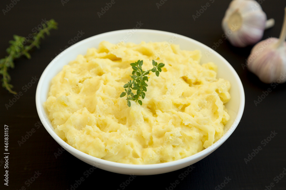 Homemade Garlic Mashed Potatoes on a black background, side view.