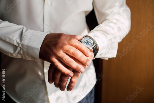 a man in a white shirt puts a watch on his hand