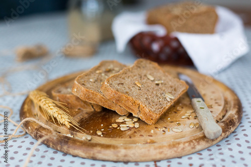 Slices of homemade rye bread with seeds, sesame seed, flaxseed on round wooden plate