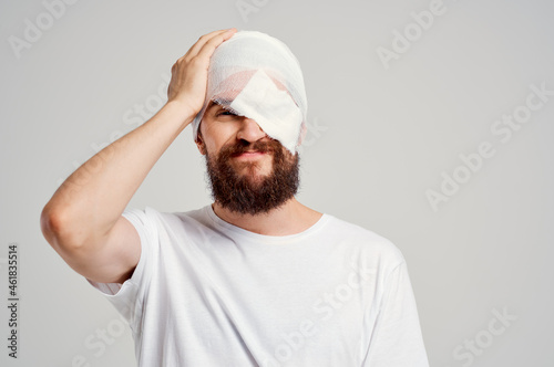 sick man with bandaged head and eye hospitalization light background