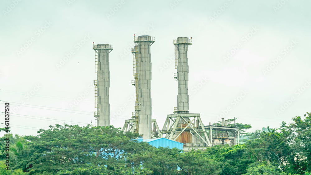 Obraz premium Funnels of industrial facility behind the tree at Mahakam riverbank, Borneo, Indonesia