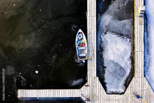 Aerial top-down view of a fishing boat in a dock in winter 