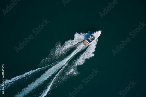 Diagonal boat movement on blue water top view. White speed boat fast movement on the water top view. Travel - image. Top view of a white high-speed boat.