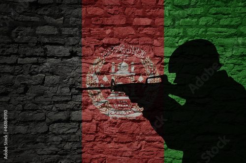 Soldier silhouette on the old brick wall with flag of afghanistan country.