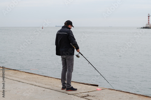 A man is standing on the pier and fishing. Sea fishing. The fisherman catches fish.