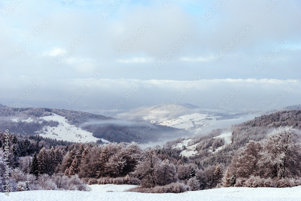 The view from the mountain glade to the snow-capped hills and forests, Beskids, Poland