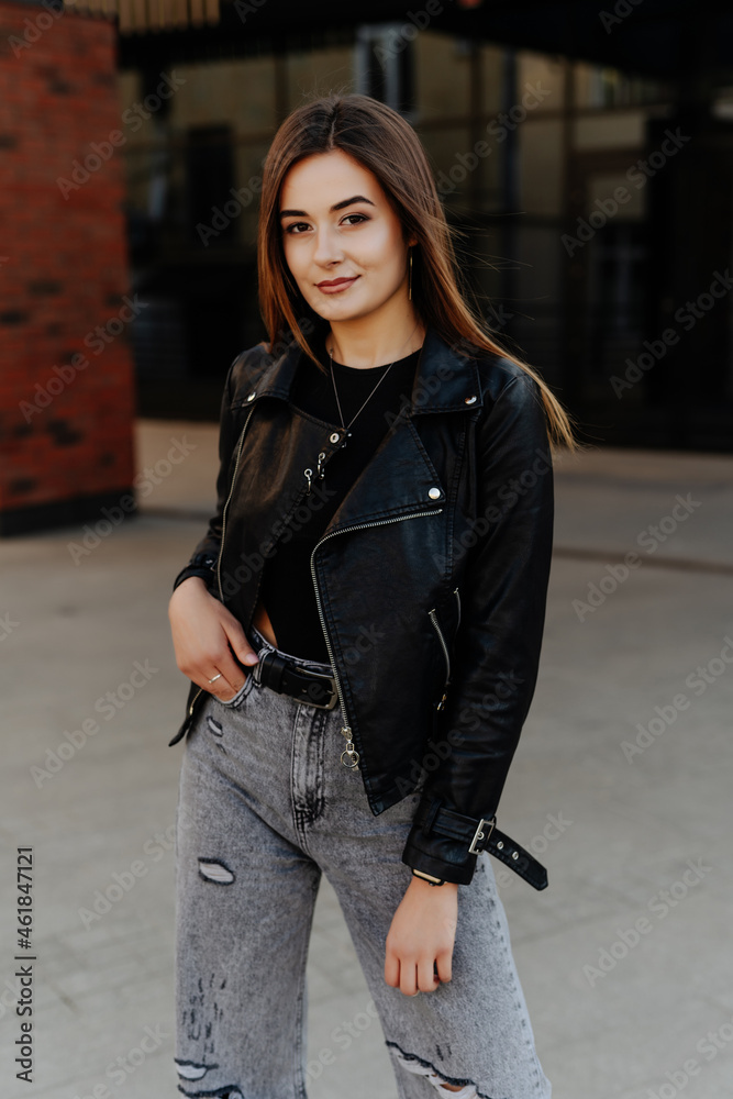 Young woman walking in leather jacket in the street
