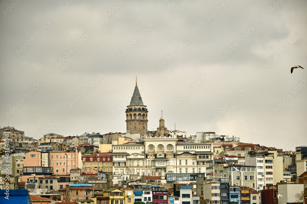 Turkey istanbul. Famous galata tower of istanbul taken photo from istanbul bosphorus. Galata tower during overcast sky and rainy day with single seagull flying over the tower.