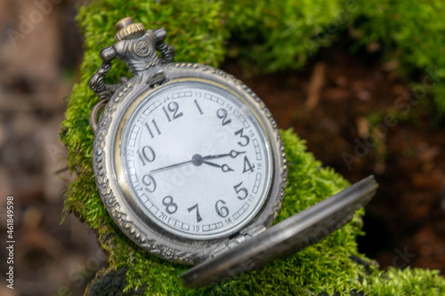 Vintage pocket watch lying on the ground, close-up, selective focus.