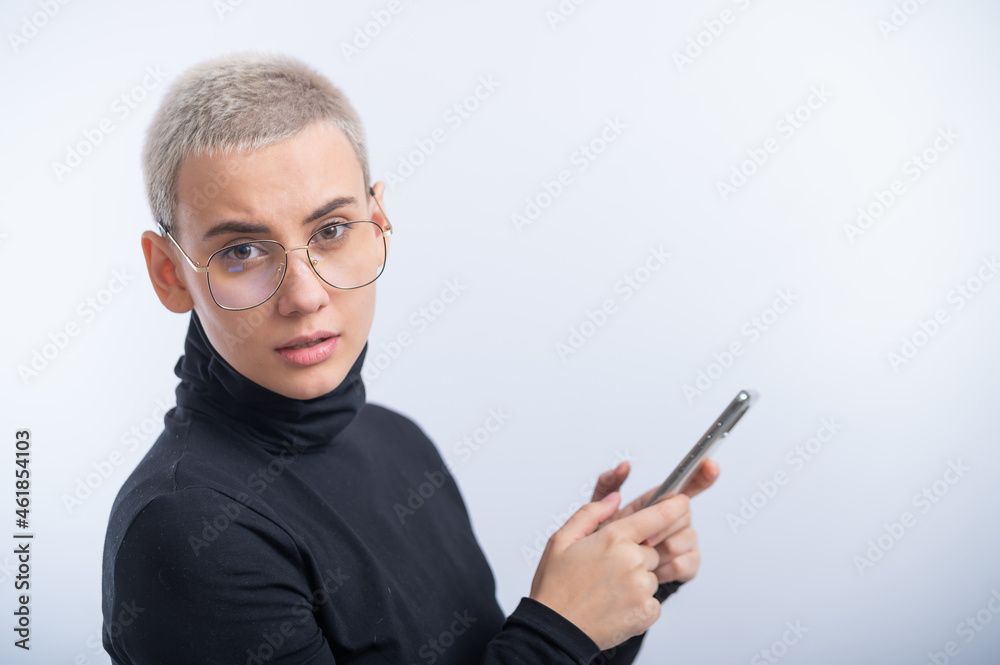 Young caucasian woman with short hair uses a smartphone on a white background. Young caucasian woman with short hair uses a smartphone on a white background.