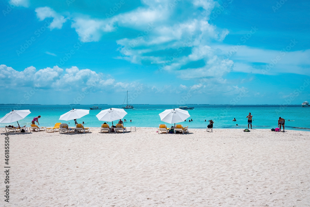 Cancun, Mexico. May 30, 2021. Deckchairs under canopy shade for resting on beach sand in front of sea with yachts. Tourists enjoying beach holiday