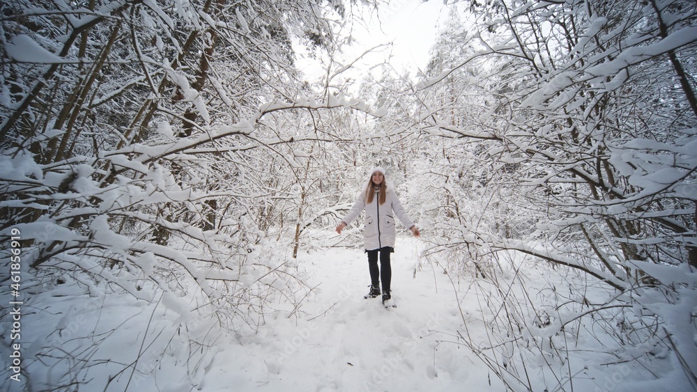 A teenage girl walks through the snowy forest.