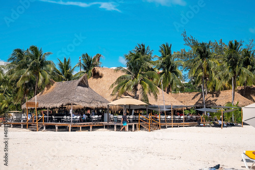 Cancun, Mexico. May 30, 2021. Tourists relaxing under straw canopy at restaurant on sandy beach during summer holiday