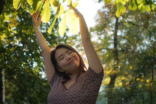 lifestyle portrait of young happy and beautiful Asian Korean woman playful and relaxed on sunset at city park enjoying free celebrating nature and Autumn colors