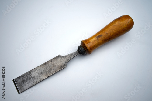 Forged metal chisel on wood with a wooden handle on white isolate. An antique hand tool for woodworking.
