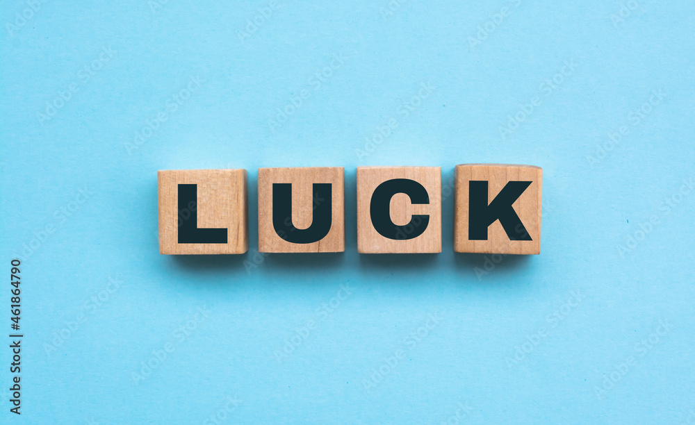 the word luck is written on a wooden cubes structure. blocks on a blue background. financial concept. selective focus. the word luck is written on a wooden cubes structure. blocks on a blue background. financial concept. selective focus.