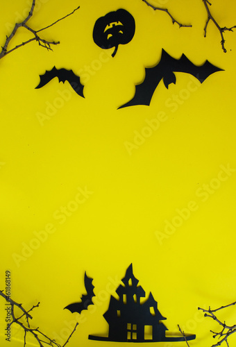 Halloween and decoration concept - bats, pumpkins, gloomy paper house, gloomy black tree branches on a yellow background. Folded paper origami art. Halloween background with cut out bats and other dec