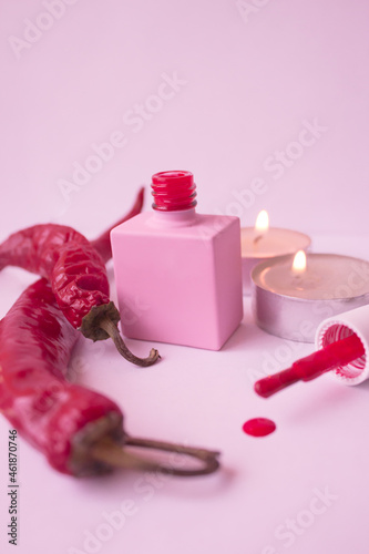 pink jar of red nail polish next to red hot pepper photo