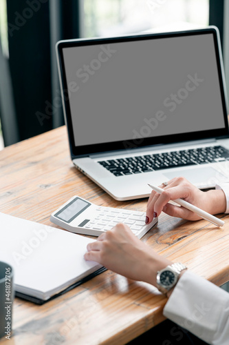 Cropped shot of woman hand using calculator while sitting at office desk, vertical view.