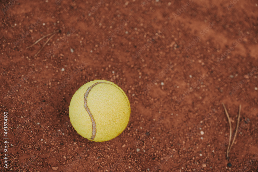 Yellow tennis ball on clay tennis court.