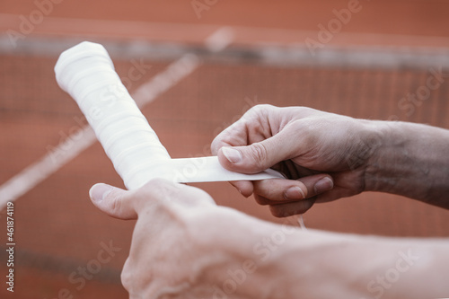Process of replacement grip on tennis racket. Overgrip. Close-up of hands.