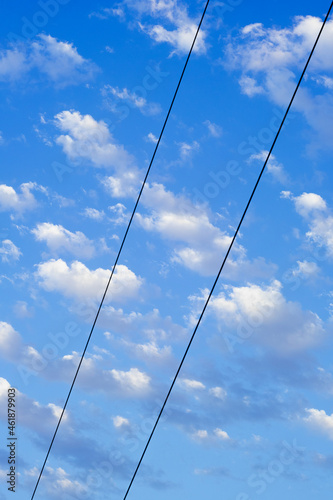 blue sky with small numerous cloud. electric wires on the background of a blue sky. diagonal