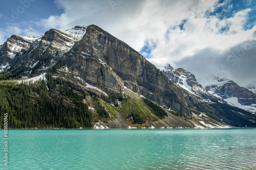 Emerald waters of Lake Louise in Banff National Park, surrounded by snow capped mountains.