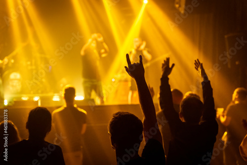 Hand horns rock sign on an anonymous metal concert, yellow flashing light stage atmosphere