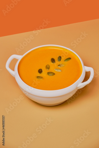 Pumpkin soup decorated basil on orange background