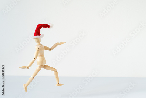 Christmas blank greeting card mock-up scene. Wooden mannequin posing on greeting card or gift list with red Santa Claus hat.Modern and minimal Santa Claus.