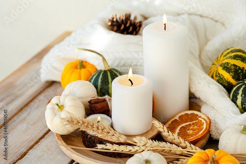 Pumpkins and candle with fairy lights around on a wooden table. Autumn season image  cozy home atmosphere. Close up. Thanksgiving family dinner table decor.