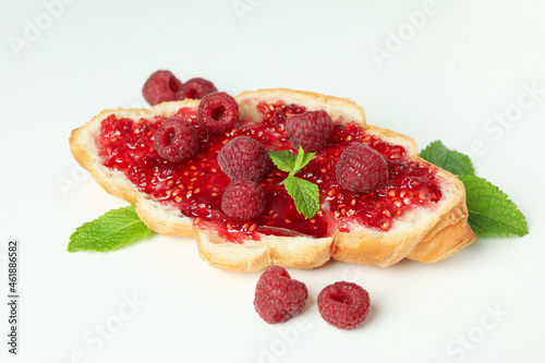 Croissant with raspberry jam on white background