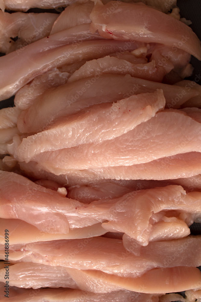 Photo of sliced chicken meat on a dark cutting board with cut marks Photo of sliced chicken meat on a dark cutting board with cut marks
