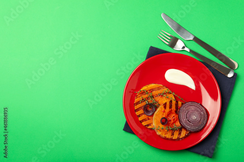 Concept of tasty food with baked pumpkin on green background
