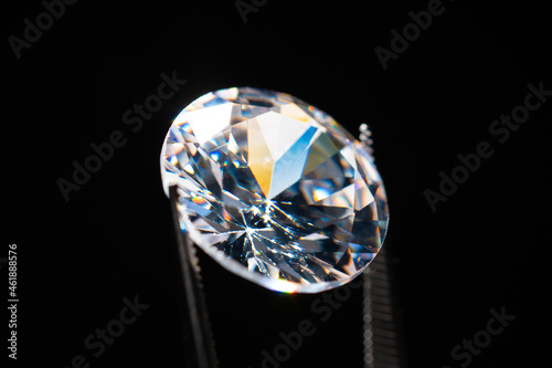 Diamond selective focus held in metal jeweller tweezers  brilliant stone cut inspection of polish quality and contamination. Natural carbon material  for industrial and fashion applications.