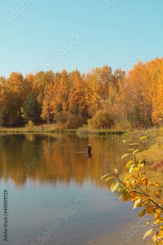European autumn landscape. Autumn in Belarus. October has come. A fisherman catches fish in the water.