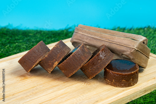 A stack of the palm sugar with dried coconut leaves used for packing. Selective focus points. Blurred background photo