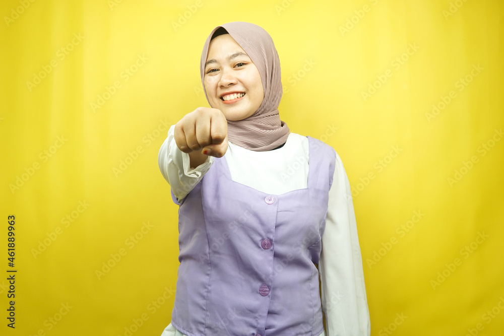 Beautiful young asian muslim woman smiling confident, enthusiastic and cheerful with fists clenched at camera, punching, fighting, cooperation, looking at camera isolated on yellow background Beautiful young asian muslim woman smiling confident, enthusiastic and cheerful with fists clenched at camera, punching, fighting, cooperation, looking at camera isolated on yellow background