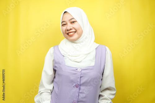 Beautiful young asian muslim woman smiling confidently, facing the camera isolated on yellow background