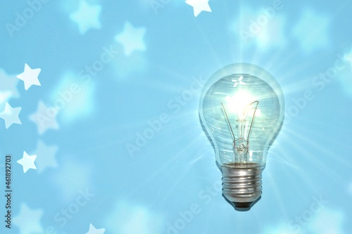 shining light bulb with stars on blue background