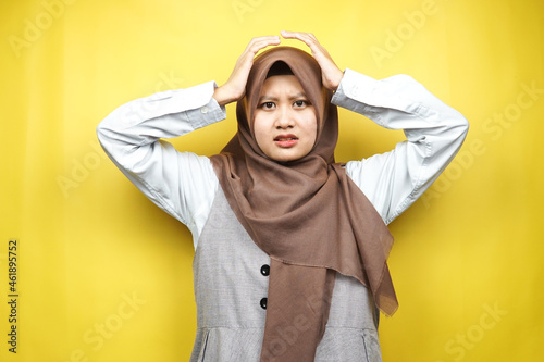 Beautiful young asian muslim woman stressed, shocked, dizzy, unhappy, many problems, want solution, with hands holding head isolated on yellow background © MunirSr