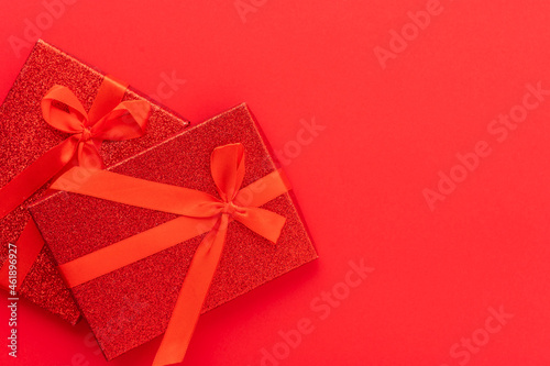 Two gifts in a red package tied with red ribbons on a red background. Stylish composition. Minimalism. Holiday, congratulations, Birthday, Christmas, New Year, Valentine's Day, family celebrations.