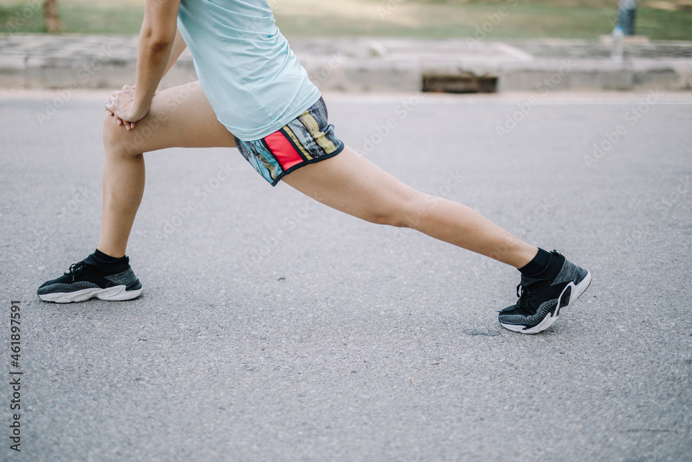A beautiful woman stretching her body before going for a run in the morning. A female runner kicks her toe to stretch. women's health care concept A beautiful woman stretching her body before going for a run in the morning. A female runner kicks her toe to stretch. women's health care concept