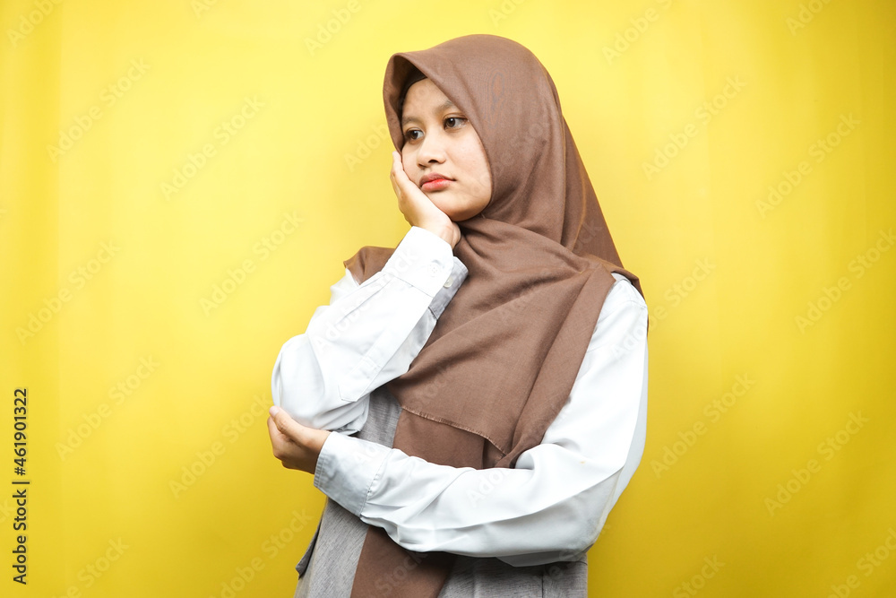 Beautiful asian young muslim woman thinking, looking for ideas, looking for solutions to problems, with hands holding cheeks, isolated on yellow background Beautiful asian young muslim woman thinking, looking for ideas, looking for solutions to problems, with hands holding cheeks, isolated on yellow background